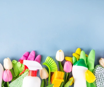 Blumen und Putzmittel vor blauem Hintergrund.