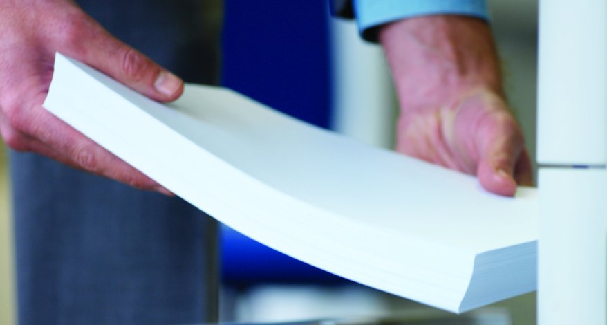 Zwei Hände halten einen Stapel Papier.