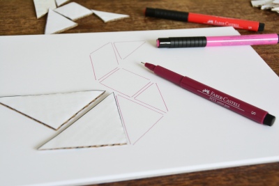 Tangram-Formen aus Pappschablonen werden mit Fineliner auf Papier gezeichnet