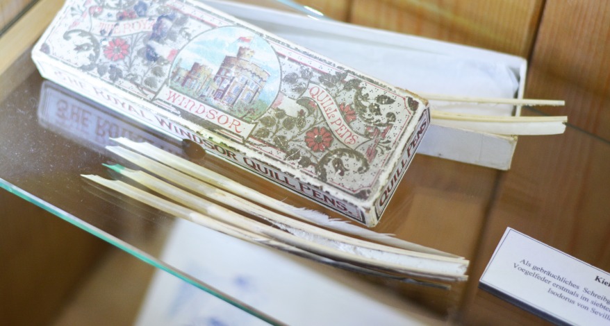 Eine historische Verpackung von Schreibfedern und Schreibfedern auf einer Glasablage.