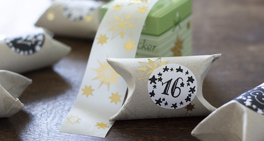 Eine Klopapierrolle, die mit einem Aufkleber mit der Nummer 16 und einem Stern-Aufkleber beklebt ist. Im Hintergrund sind weitere Rollen mit Nummern zu sehen und Stern-Aufkleber von Avery Zweckform.selbst gebastelt