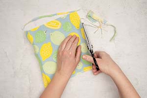 Ein Stück gemusterter Stoff wird mit einer Zickzack-Schere zu einem Quadrat zurechtgeschnitten. Foto: Johanna Rundel