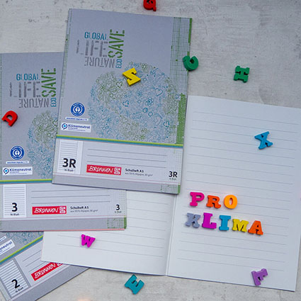 Auf einem hellen Untergrund liegen mehrere Recycling-Schreibhefte von Brunnen mit Lineaturen für die erste bis vierte Klasse. Auf einem aufgeschlagenen Heft wurde mit bunten Radiergummi-Buchstaben "pro Klima" geschrieben. Weitere Buchstaben sind auf den Heften verteilt. Foto: Johanna Rundel