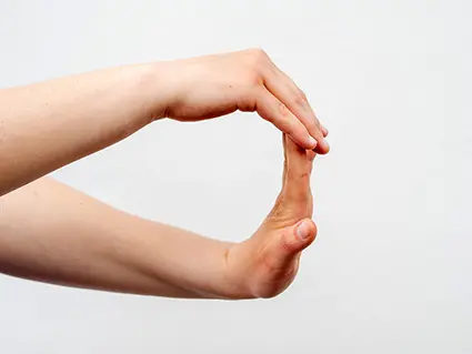 Jemand führt eine Handgelenksdehnung mit beiden Armen aus. Man sieht die Arme vor einem weißen Hintergrund.