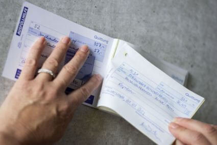 Jemand löst an der Perforation eine Quittung aus einem Quittungsblock von Avery Zweckform.