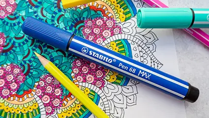 Ein dicker blauer Filzstift von Stabilo liegt auf einem fast fertig ausgemalten Mandala.