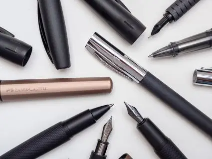 Viele verschiedene, hochwertige Füller und Tintenroller von Faber-Castell liegen kreuz und quer verstreut auf einem hellen Untergrund. Foto: Johanna Rundel