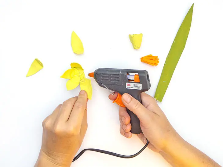 Jemand klebt mit einer Heißklebepistole von KNORR prandell gelbe Blütenblätter aus Eierkarton auf einen kleinen Kreis. Foto: Johanna Rundel