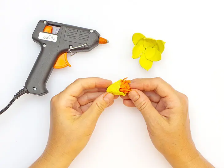 Jemand klebt eine in Fransen geschnittenen Rolle orangefarbenes Krepppapier von HEYDA in eine gelb angemalte Spitze eines Eierkartons. Foto: Johanna Rundel