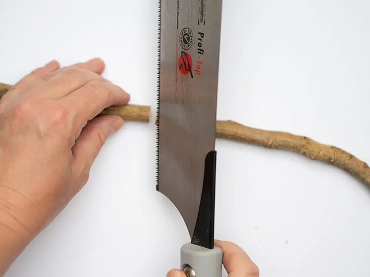 Jemand sägt mit einer Handsäge einen Stock in zwei Teile. Foto: Johanna Rundel