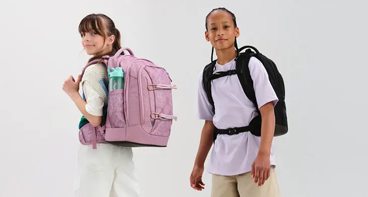 Zwei Jugendliche mit ihren Schulrucksäcken von satch vor weißem Hintergrund.