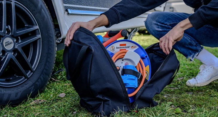 Person verstaut Kabeltrommel in wetterfester Transporttasche