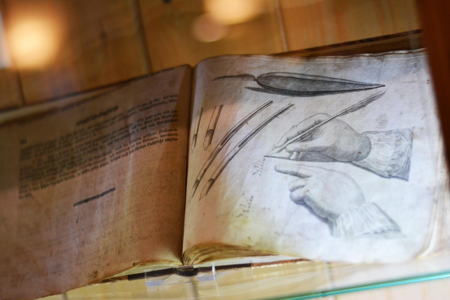 Abbildung einer Seite aus einem Buch, auf der 2 Schreibfedern und die Haltung der Feder in der Hand gezeigt werden.