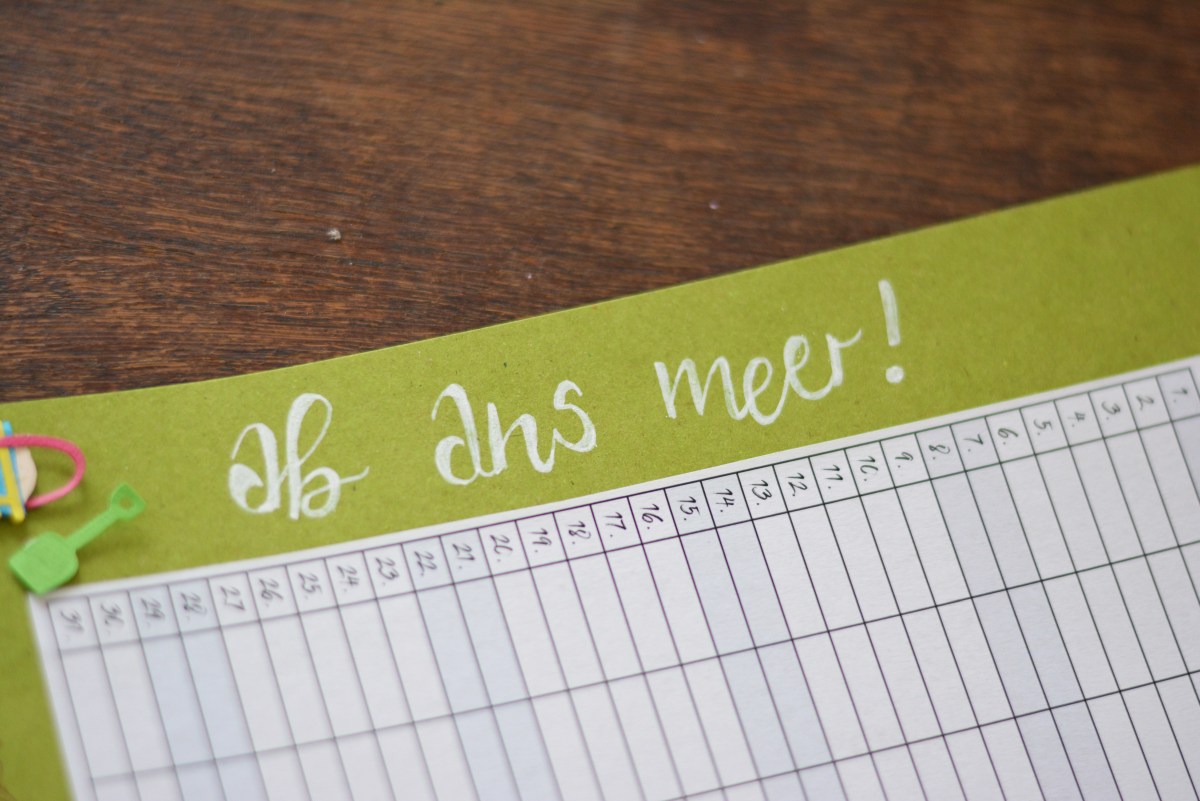 Handlettering „Ab ans Meer!“ auf grünem Karton über Monatsplan.