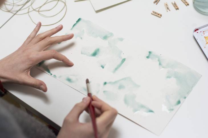 Grüner Aquarellhintergrund wird mit Pinsel auf Papier gestaltet