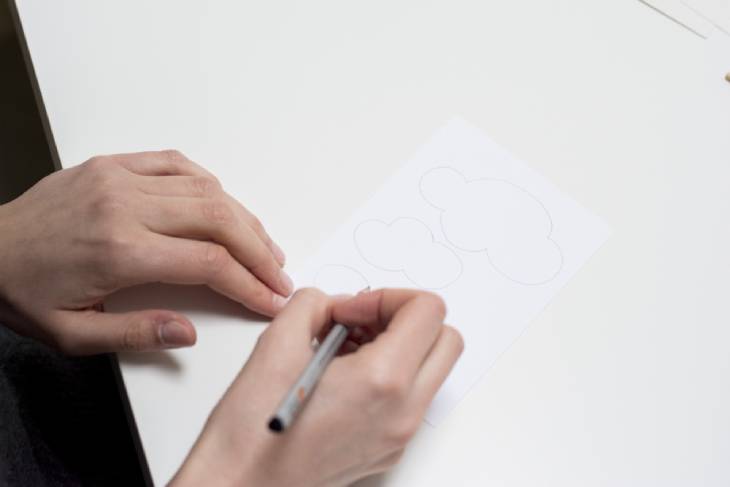 Hand zeichnet Wolkenform mit schwarzem Stift auf weißem Papier