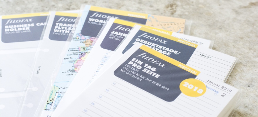 Filofax-Einlagen mit Karten und Planerblättern auf Steinboden