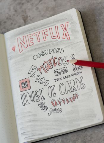 Seite eines Notizbuches, auf der diverse Seriennamen aufgemalt wurden.