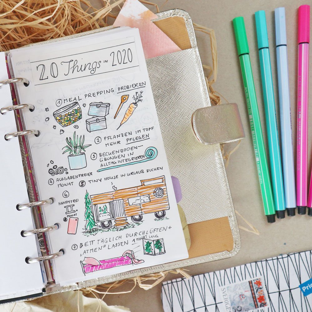 Eine Seite in einem Filofax-Kalender ikst mit vielen bunten Elementen gestaltet. Daneben liegen bunte Stabilo Fineliner.