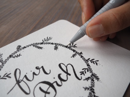 Nahaufnahme beim Zeichnen eines Kranzes auf einer Karte mit einem Fineliner