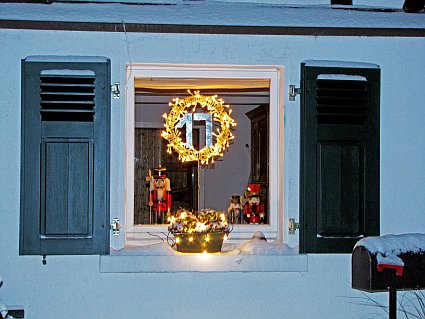 Weihnachtlich beleuchtetes Fenster mit Lichterkranz und Nussknacker-Deko.