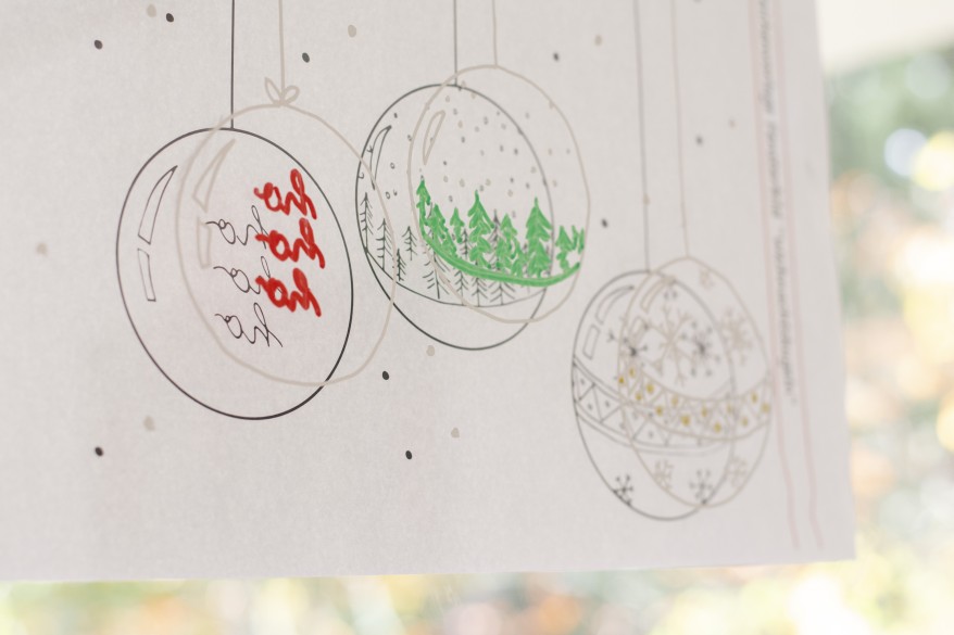 Auf einem Blatt sind 3 Weihnachtskugeln aufgedruckt. Das Blatt klebt an einem Fenster und die Kugeln wurden mit weißer Fensterkreise auf das Fenster übertragen.