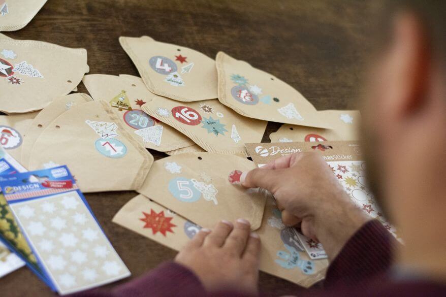 Diverse Kaffeefilter werden mit Stickern mit Weihnachtsmotiv von Avery Zweckform beklebt.