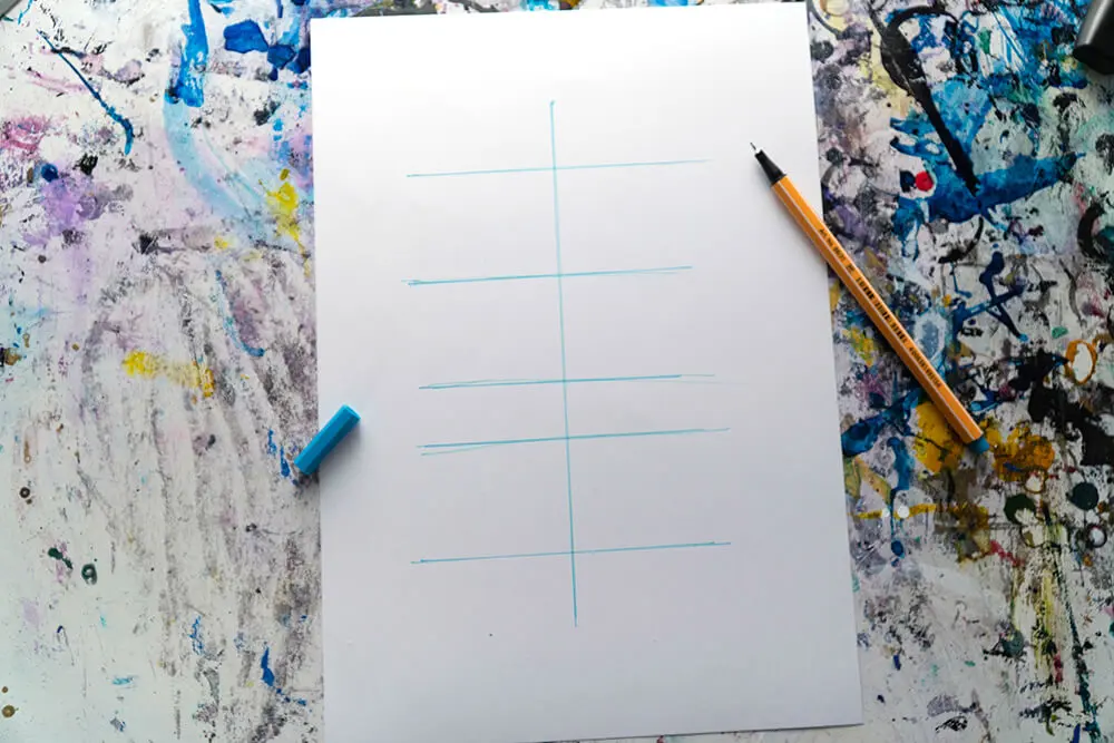Auf einem weißen DIN A4 Blatt sind hellblaue Linien für ein Lettering vorgezeichnet. Daneben liegt ein Fineliner von Stabilo.