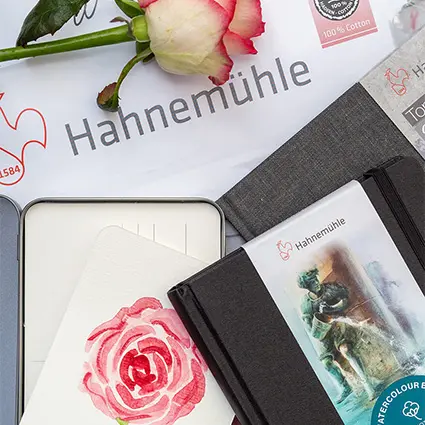 Verschiedene Aquarellblöcke, Aquarellpostkarten und Aquarellskizzenbücher von Hahnemühle liegen auf- und nebeneinander auf einem hellgrauen Untergrund.