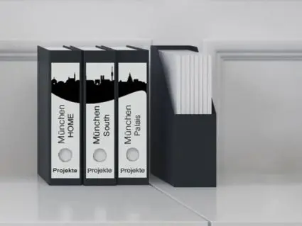 Vier schwarze Aktenordner mit einem Panoramadesign-Etikett von Avery Zweckform auf dem Rücken stehen vor einer weißen Wand.