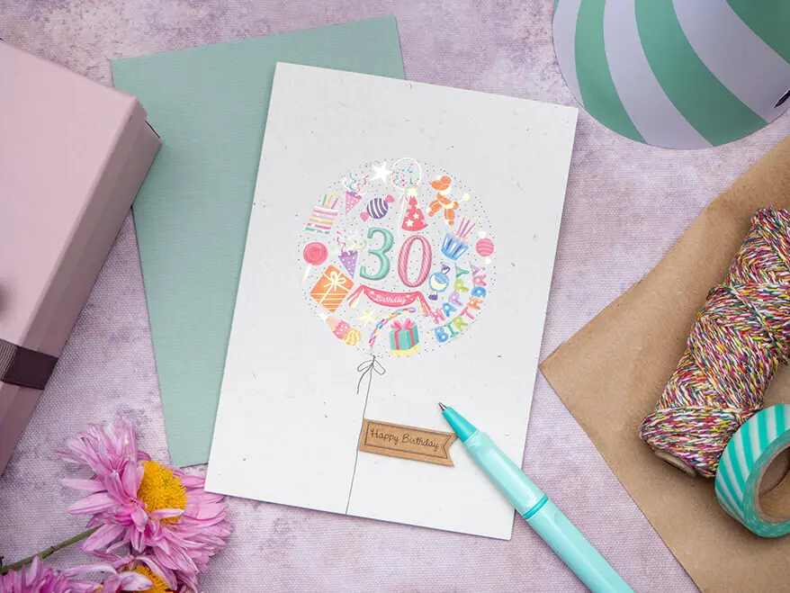 Eine aus bunten Aufklebern von Rössler selbstgebastelte Glückwunschkarte zum 30. Geburtstag liegt auf einem rosa Untergrund. Foto: Johanna Rundel 