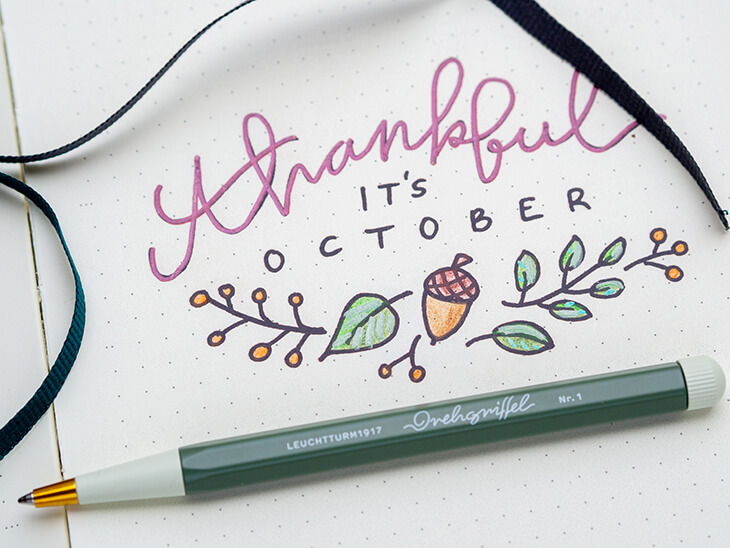 Monatsdeckblatt für Oktober in einem Bullet Journal von LEUCHTTURM1917. Das Motiv: Der Schriftzug „thankful it´s october“, darunter ein Doodle mit Herbstmotiven. Foto: Johanna Rundel