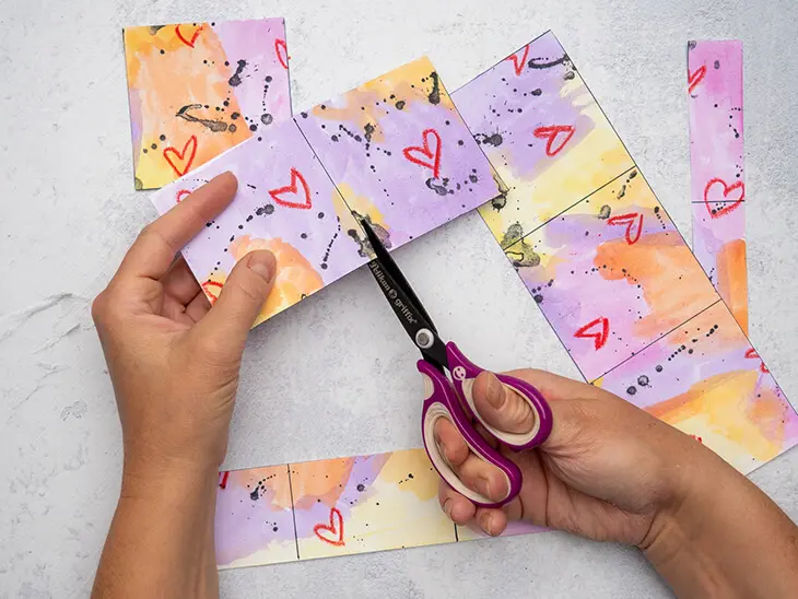 Jemand schneidet mit einer Pelikan-Schere Quadrate aus einem Papier. Foto: Johanna Rundel