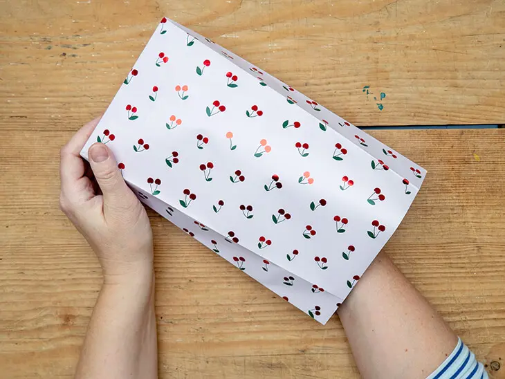 Jemand öffnet eine selbstgebastelte Geschenktüte aus einem Geschenkpapier von STEWO. Foto: Johanna Rundel