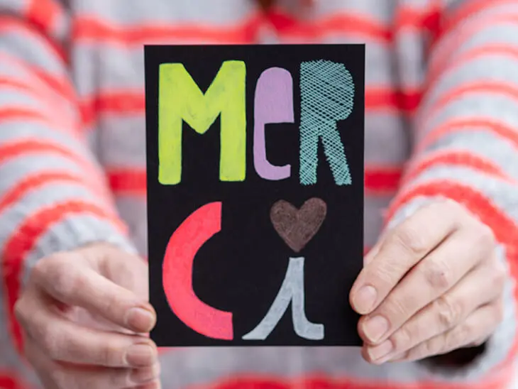 Jemand hält eine, mit Stiften von Sakura handgeletterte, Karte mit dem Wort „Merci“ in die Kamera. Foto: Johanna Rundel