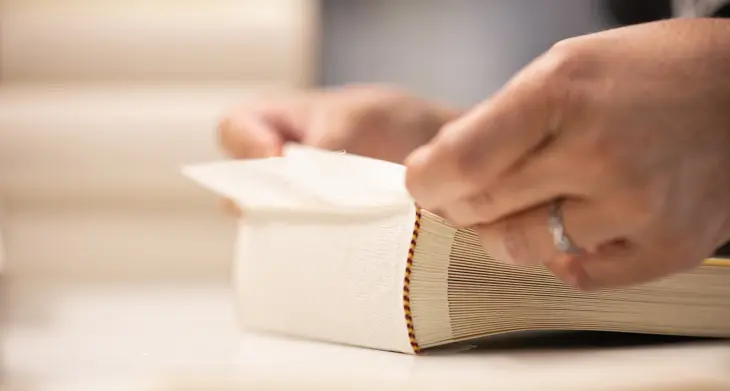 Detailaufnahme einer Hand, die ein Fotoalbum von Semikolon bindet.