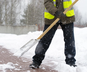 Mann mit Schneeschüppe befreit Weg von Schnee