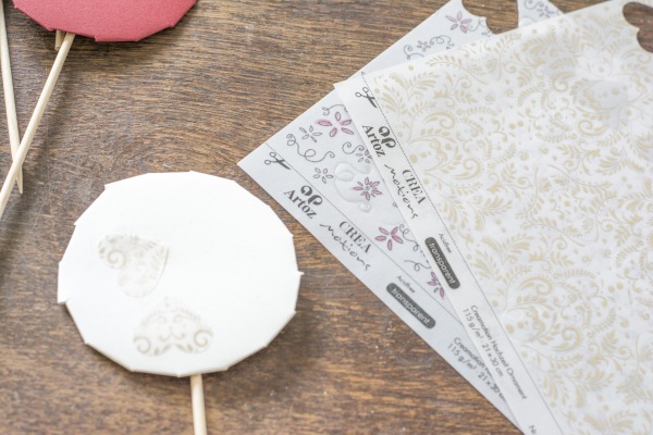 Auf einem runden Papier sind in Herzen aus goldenem Transparentpapier aufgeklebt