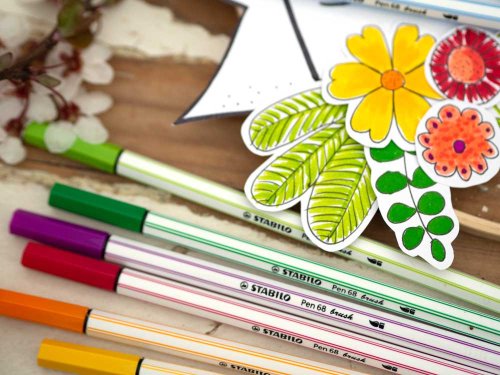 Bunte Stabilo Filzstifte und ausgeschnittene bunte Papier-Blumen auf Tisch