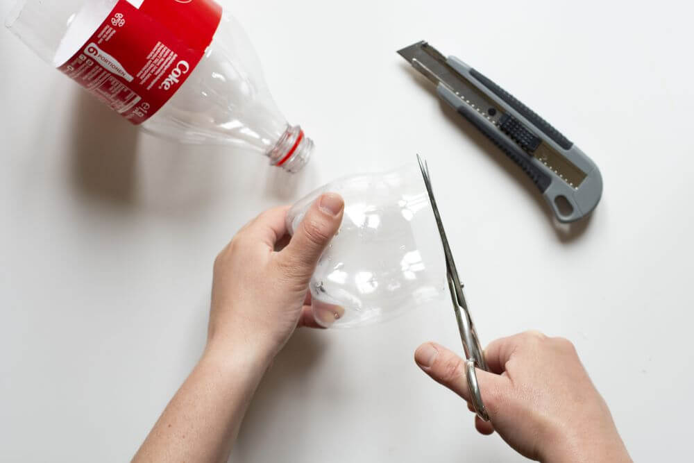 Von einer PET-Flasche wir der Boden mit Hilfe einer Schere und eines Cutters abgeschrieben.