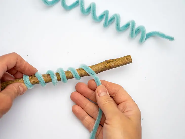 Jemand wickelt einen türkisen Chenilledraht von KNORR prandell um einen Stock. Foto: Johanna Rundel