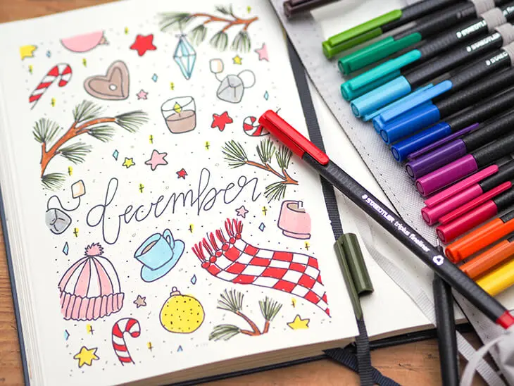 Dezember-Deckblatt im BuJo, daneben bunte Fineliner von STAEDTLER. Foto: Johanna Rundel