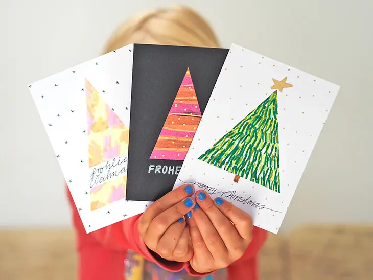 Ein Kind hält drei selbstgebastelte Weihnachtskarten in die Kamera. Foto: Johanna Rundel