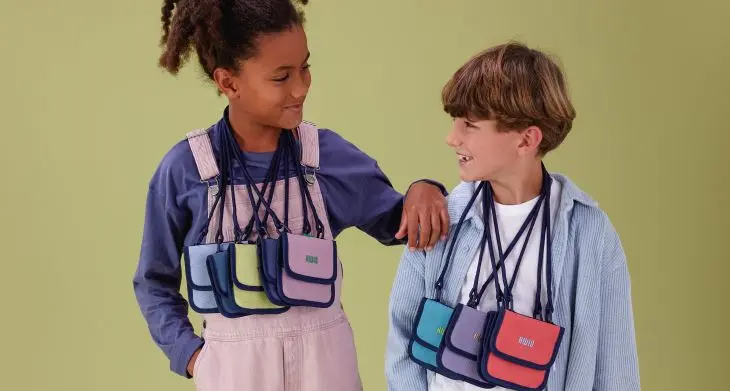 Zwei Kinder blicken sich an, um ihren Hals hängen mehrere Brustbeutel SNAPP von KWIO