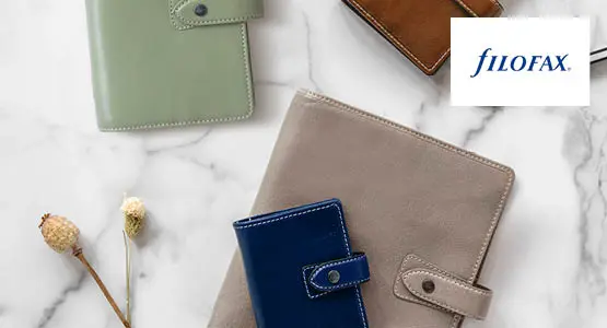 Nahaufnahme mehrere Kalender und eines Kugelschreibers von Filofax. Rechts oben ist das Logo von Filofax abgebildet.