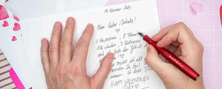 Jemand schreibt mit einem Füller eine Valentinstagskarte