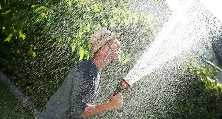 Mann wässert seinen Garten.