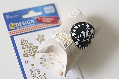 Blisterverpackung der z-Design Aufkleber von Avery weckform mit goldenen Tannenbäumen. Darauf liegt eine Klopapierrolle, die damit beklebt ist.