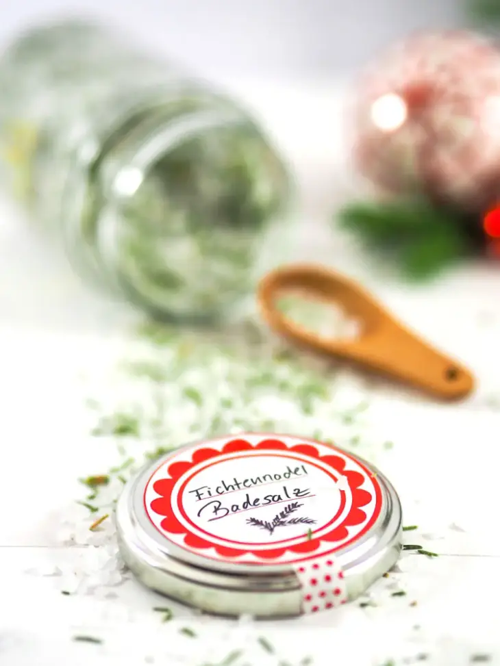 Nahaufnahme eines Marmeladendeckels auf den ein Etikett mit der Beschriftung „Fichtennadel Badesalz“ geklebt ist