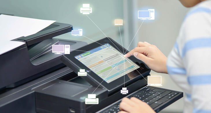 Nahaufnahme des Bedienfeldes eines modernen Druckers. Jemand tippt mit dem Finger aufs Display. Als grafische Elemente sind viele kleine Icons in das Foto gebaut, die jeweils mit einem Strich zum Zeigefinger rund um das Display angeordnet sind. Die Icons stellen unter anderem Drucker, Monitor und Computer dar. 